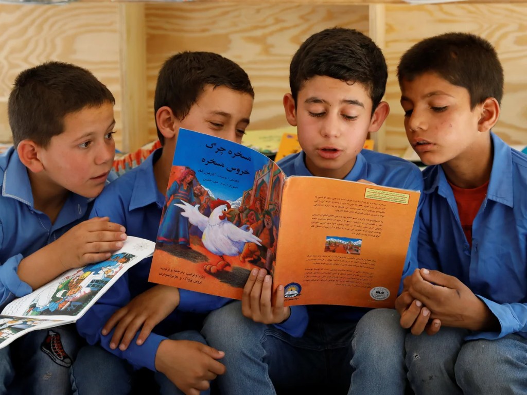 Afghan schoolboys reading a Dari picture book together