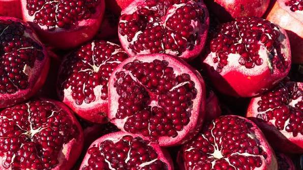 Halved pomegranates piled together, their red seeds exposed